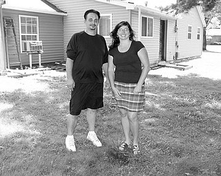 FEDERAL HELP: Christopher Wargo, left, and his wife, Alissa, stand at the rear of their home on Pleasant Valley Road in Vienna Township. The small area of dirt in front of them is the only indication on their property that they even have a septic system. It empties into a ravine at the back of their property. The couple has been approved to receive federal stimulus money to replace the system, which didn’t meet regulations when the Wargos bought the house in 2005.