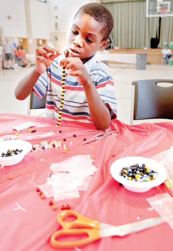 Walter Talley, 6,  of Youngstown, makes a bracelet while at the "Kids Fun Fair" at The Salvation Army on Glenwood Ave., Wednesday afternoon. 