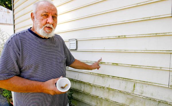 ONE FAMILY’S STRUGGLE: Francis Humphries, of Albert Street, holds a bullet and shell casing he collected on his property after his home was recently hit with gunfire. He can point to the multiple bullet holes in the siding of his house and has taken to recording late-night activity around his home.