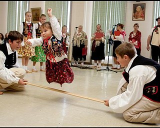 The Vindicator/Geoffrey Hauschild
Sophie Heschmeyer, 3, jumps over a stick held by Drew Heschmeyer, 14, and Jacob Nash, 13, during traditional dances by Krakowiaki Polish Folk Circle during the second annual Polish Day Festival at St. Anne Church in Austintown on Sunday afternoon. 
8.30.2009