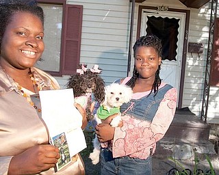 TREASURED MEMENTO: Tina Fleisher holds a letter from Michelle Obama and a photo of Bo, the Obamas’ Portuguese water dog, that she received from the White House. Her daughter, Cleopatra Butler, cradles the family’s pet poodles, Diamond Louise and Jamie Foxx, who produced two puppies that the Fleishers had offered to the Obama family.