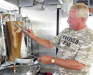 FRESH CUT:  Vendors at the Canfield Fair cater to thousands of patrons a day. Here, Roger Mace, of Wintersville, slices some meat for a gyro sandwich at the 163rd edition of the fair.