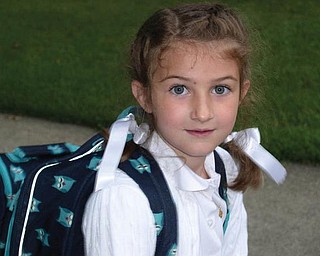 Maddie Moran patiently waits for the school bus for first grade at St. Charles School.       