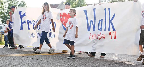 BIG BANNER: Out in front for Lake Milton’s second annual “America Supports You” Freedom Walk was a large “Remember 9-11” banner. Walkers on Thursday showed support for the U.S. military, and remembered victims of the Sept. 11, 2001, terrorist attacks on America.