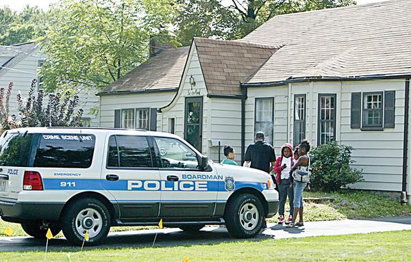 HOUSE RAIDED:  A Boardman police officer talks to people outside 65 Leighton Ave. in the township after officers and members of the U.S. Marshal’s Special Task Force raided the home. Drugs and money were confiscated at the home Thursday morning.