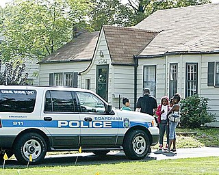 HOUSE RAIDED: A Boardman police officer talks to people outside 65 Leighton Ave. in the township after officers and members of the U.S. Marshal’s Special Task Force raided the home. Drugs and money were confiscated at the home Thursday morning.