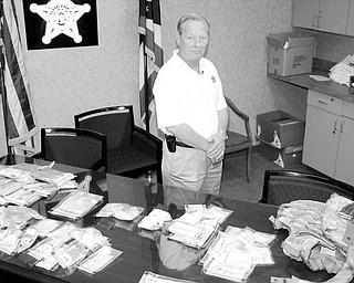 BIG HAUL: Trumbull County Sheriff Thomas Altiere stands near a table full of  drugs, cash, a bulletproof vest and ammunition that were recovered  from a house at 2026 W. Market St. in Warren during a raid Tuesday afternoon. Fourteen people were arrested at the house on drug charges, 11 of whom will be arraigned today in Warren Municipal  Court. The lead investigative agency was the Trumbull  Ashtabula Group Law Enforcement Task Force, which is headed by Lt.  Jeff Orr of the sheriff’s department.