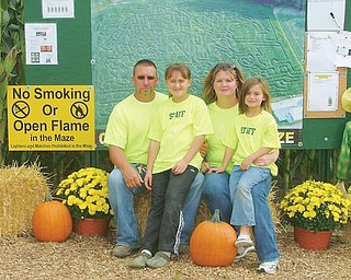 AMAZING fmaily: The Bacon family of New Springfield, from left, Mike; Cassie, 9; Cindy; and Carlee, 6, have commissioned construction of a maze in a large cornfield in Fairfield Township, Columbiana County. The maze is open Friday evenings and weekends and other times by appointment.