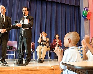 WITH HONOR: McGuffey Elementary kindergartners Bernard Thomas, right, and Timothy Davis applaud as Richard Scarsella, president of the William Holmes McGuffey Historical Society, honors Gilbert “Gibby” James of Canfield, far left, with the fourth annual Pioneer Award. The award is given to local individuals for notable contributions to literacy and historical preservation of the Mahoning Valley.