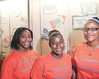 PEACEMAKERS: Youngstown students, from left, Mallory Kimble, Janae Ward and A’Ja Glover, stand in front of a message board at Chaney Middle School featuring quotes on nonviolence. The three organized a project to reduce violence in their schools. 