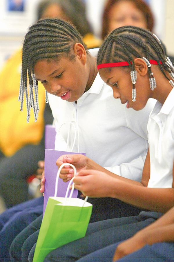 ACHIEVEMENT GIFT: Andre McCoy (left) and A’zha Cross, fourth graders at Youngstown Community School, peek inside their gift bags at the iPods they received as a gift for passing all of their Ohio Achievement tests as third graders last year. A total of 77 students earned the gifts from businessman Edward Muransky who is a member of the school’s governing authority.