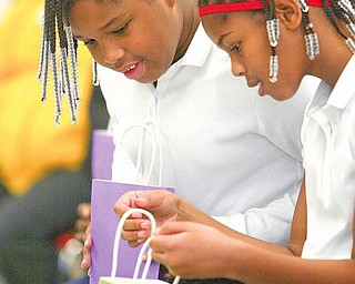 ACHIEVEMENT GIFT: Andre McCoy (left) and A’zha Cross, fourth graders at Youngstown Community School, peek inside their gift bags at the iPods they received as a gift for passing all of their Ohio Achievement tests as third graders last year. A total of 77 students earned the gifts from businessman Edward Muransky who is a member of the school’s governing authority.