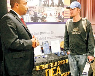 LOOKING FOR A JOB: Cory Rider, right, of Newton Falls, a junior at Youngstown State University, talks with Christopher Taylor with the Detroit office of the federal Drug Enforcement Administration about a career in law enforcement during the 2009 Job Expo at the university.