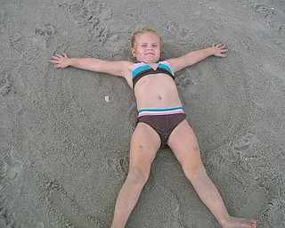 Ava Bosnjak of Boardman is making sand angels at Myrtle Beach, N.C., in August.