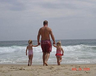 Brandon Bower of Austintown enjoys a stroll on the beach with his two girls, Brelyn, 4, and Kaelyn, 2.