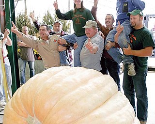 WE ARE THE CHAMPIONS: Christy Harp and her husband, Nick, are lifted up after setting a record for heaviest pumpkin at The Ohio Valley Giant Pumpkin Growers weigh-off. The Massillon couple’s pumpkin weighed 1,725 pounds at the event Saturday at Parks Garden Center in Greenford.