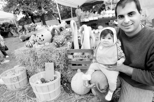 Carl Angiuli and his 8-month-old daughter, Gisella, above, pose near some gourds at a booth for Angiuli’s Farm Market in Canfield. 