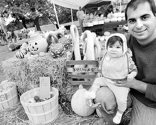 Carl Angiuli and his 8-month-old daughter, Gisella, above, pose near some gourds at a booth for Angiuli’s Farm Market in Canfield. 