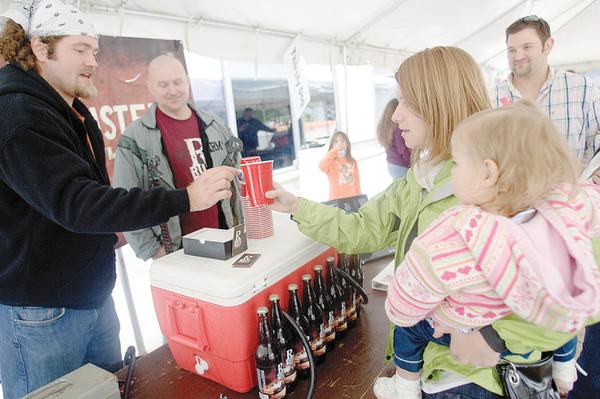 Autumn Andrews of Petersburg, holds her neice 19 month old Camille Andrews, while receiving a rust belt beer from Rust Belt Brewing Co.'s Brewmaster, Nick Rosich, of Pittsburgh as he stands alongside the brew company's president and youngstown resident, ken blair. 