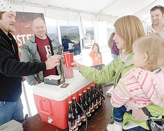 Autumn Andrews of Petersburg, holds her neice 19 month old Camille Andrews, while receiving a rust belt beer from Rust Belt Brewing Co.'s Brewmaster, Nick Rosich, of Pittsburgh as he stands alongside the brew company's president and youngstown resident, ken blair. 