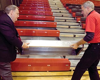 A NEW NOTION: Canfield Local Schools Superintendent Dante Zambrini, left, assists high school athletic director Greg Cooper with a removable first step to the school gymnasium’s new bleachers. The school district completed a renovation project, which cost about $300,000, and replaced the gym floor as well as the bleachers.