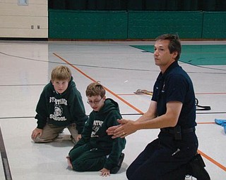 FIRE SAFETY: Members of the Hubbard Volunteer Fire Department spent the afternoon recently with students at St. Patrick School for Fire Safety Month, which is October. Below, fourth-grader Daniel Robinson tries on the gear that firefighters wear going into a fire. Above, Daniel and schoolmate Vito DiTomasso listen intently as volunteer fireman Jim Petro gives fire safety tips. Students learned to “Stop, Drop and Roll” if their clothing were to catch fire and were taught the importance of having working smoke detectors in their homes. After the indoor lessons, students went outside to see a firetruck and the equipment firefighters use, including the Jaws of Life.