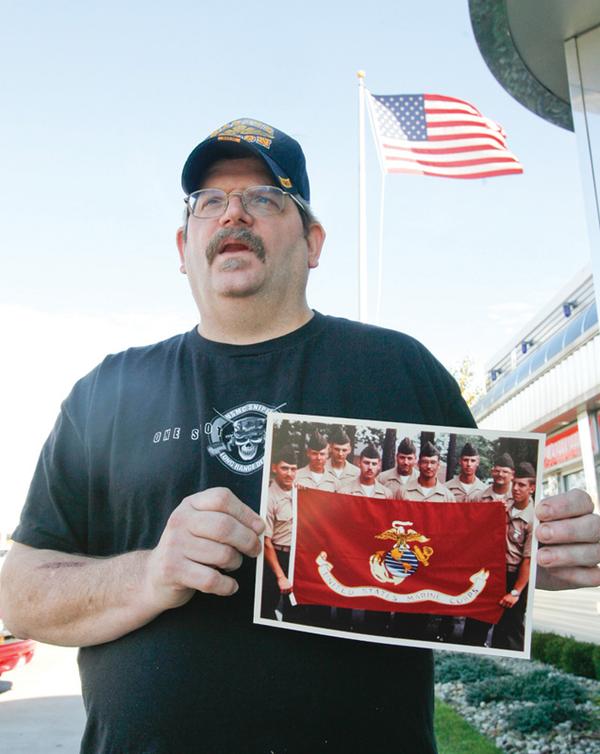 SOMBER REMINDER: Anthony Kolat of New Middletown holds up a picture of fellow Marines with whom he served. He was on one side of a compound in Beirut, Lebanon, on Oct. 23, 1983, when a suicidal truck bomber killed 241 U.S. service members, 220 of whom were Marines.