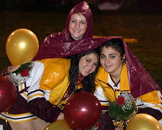 "South Range cheerleader, Emma Lewis, helps fellow cheerleaders Kim
Miglets and Alex DeRose keep dry before Friday evening's rainy
football game."