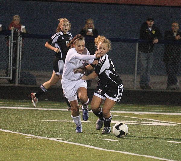 BALL BATTLE:  Fitch’s Christian Goleno, left, battles Canfield’s Gia Nigro for the ball during Monday’s Division I district semifinal girls soccer game in Austintown. The Cardinals won 1-0 in overtime.
