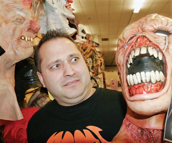 SCARY JOB: Jeff Lyda, co-owner of Halloween Mania in Austintown, checks out masks at the store. He said a lack of stress is making Halloween a popular adult event.