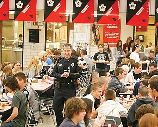 GETTING REACQUAINTED: Canfield Patrolman Paul Lasky walks through the cafeteria of Canfield High School and converses with students. Lasky returned to his place as the school resource officer for Canfield Local Schools on Monday after a two-month absence.