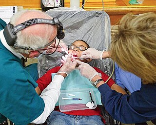 DOUBLE CLEANED: Justin Peters, a third-grader at Market Street Elementary School in Boardman, has his teeth cleaned and checked by Dr. Ronald Bell and Jan Madigan. The dentist and hygienist are part of a mobile-dentist program that tours Northeast Ohio schools. The program was in the Boardman school district Thursday.