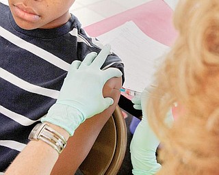 VACCINATION STATION: Damarcus Cospy, 14, gets the H1N1 vaccine from Donna Beistel, a registered nurse, at the Canfield High School clinic on Friday. About 1,500 students were given the vaccination, a school nurse said.