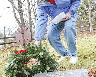 WITH RESPECT: Hugh Earnhart of Poland lays a wreath on a gravestone Monday at Zion Lutheran Cemetery in Boardman. Earnhart helped organize the wreath-laying ceremony last year with the help of the Ohio State University Extension Master Gardeners. Twenty-eight veterans were honored with wreaths that were placed by their graves.