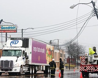 CROSSING THE LINES: Ohio Edison crews and Youngstown firefighters work to repair downed power lines  across the top of a semitractor-trailer in the southbound lane of Market Street. The truck hit the low-hanging lines Wednesday while trying to turn into the parking lot of a McDonald’s Restaurant on Market Street.