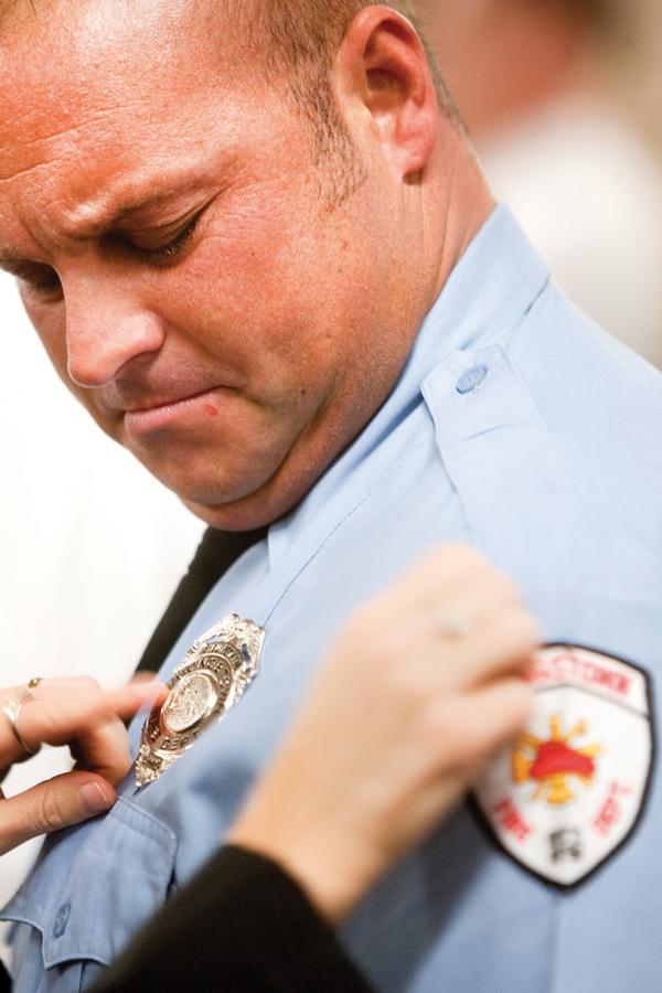 NEW ASSIGNMENT: Lt. Chris Weaver of Youngstown has his new badge pinned  to his shirt by his wife, Tammy, after a swearing-in ceremony of new officers Wednesday at the main fire station. Weaver is one of six new lieutenants in the Youngstown department.