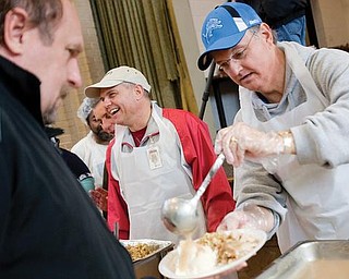 SERVING: State Rep. Ron Gerberry pours gravy over mashed potatoes as Ron Massullo of Poland, regional liaison for Secretary of State Jennifer Brunner, shares a laugh with dinner-goers  at the Salvation Army’s annual Thanksgiving feast. They were among 80 to 100 volunteers serving Wednesday’s lunch at the Glenwood Avenue facility on the city’s South Side. 