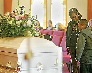 QUIET MOMENT: Rasheedah Hudson of Youngstown and her son, Charles, 4, pause for quiet reflection at the coffins of Wilneice Green and her daughter, Ja’Brayasia, during the funeral service Monday. Pastor Sylvia Jennings of Oak Baptist Church, Youngstown, where the Greens attended, offered the eulogy.