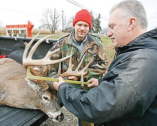 TROPHY BUCK: Kevin Dean, 45, of Alliance, left, watches as Mike Runzo of Beloit, owner of Runzo’s Outdoor Sports, measures the antlers of a 16-point buck shot by Dean. Dean, who has hunted for 16 years, said he enjoys the hobby because it is relaxing.