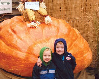 Friends Seth and Ian are having fun standing beside this huge pumpkin.