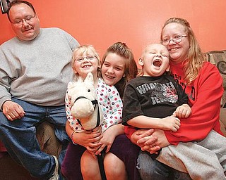 HAPPY FAMILY:  The Howard family, from left to right, includes Mike, Sydney, half-sister Paige DeRhodes, Mikey and Nancy. They’re are all smiles on a couch in their Boardman home. Mikey has leukemia and receives treatment at the Akron Children’s Hospital Mahoning Valley Beeghly Campus in Boardman.