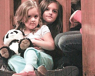 WATCHING: Marissa Orbin, 4, is held by her sister, Angelina, 7, during St. Nick’s visit.