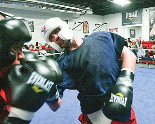 TAMING THE COBRA: World middleweight boxing champion Kelly “The Ghost” Pavlik lays a right hand into the cringing Ken “The Cobra” Sigurani at the South Side Boxing Club. Siguarani, an up-and-coming fighter, went four rounds with Pavlik at an open workout at the club Tuesday.