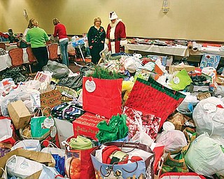 GIVING SEASON: Carol Hitchcock, owner of Home Instead Senior Care, and Santa survey a pile of gifts donated to the Be a Santa for a Senior program. The program will distribute more than 2,500 gifts to about 620 seniors.