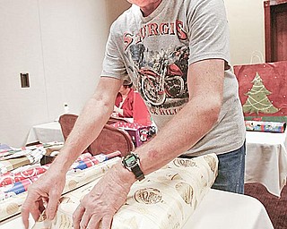 GIVING BACK: John Koontz carefully wraps a present for a senior. Koontz’ whole family volunteered last year for the Be A Santa for a Senior program.