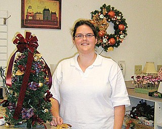 CHRISTMAS DECOR: Lindsay Castrucci, who works at the Lemon Tree in Salem, shows how bows are now being placed on the top of Christmas trees.