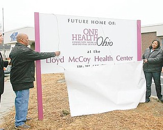 HONORABLE PLACE: Dr. Ronald Dwinnells, far left, chief executive officer of Ono Health Ohio, watches as Lloyd McCoy Sr. and Pam McCoy, at right, unveil the sign for the new medical/dental facility in the Southeast Warren neighborhood. It was announced Monday the facility would be named after the McCoys’ son, Lloyd Jr., who was shot and killed earlier this year. At far right is U.S. Rep. Tim Ryan of Niles, D-17th.