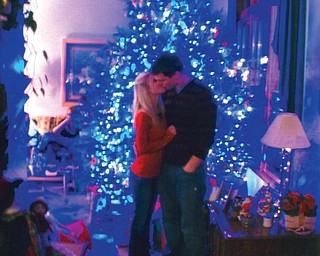 Billy Speece of Canfield and his girlfriend, Ashley Gresh of Canfield, share a kiss in front of the family's Christmas tree, which they found at the Speece Tree Farm in Canfield.