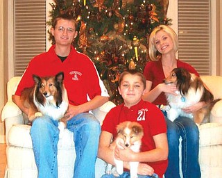 Seated in front of the family Christmas tree, Andrew, Dana and Ross Duffett welcome their new puppy, Frankie, to the family. Joining them are their other dogs, Sophie and Josie.