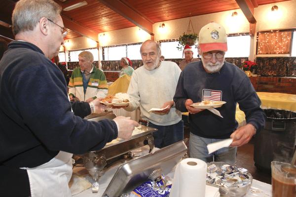 The Vindicator/Lisa-Ann Ishihara -- Gary Robinson of Warren fills the plates of Tim Austin and Art Kantner at Aulizio's Banquet Center in Warren for the free christmas dinner